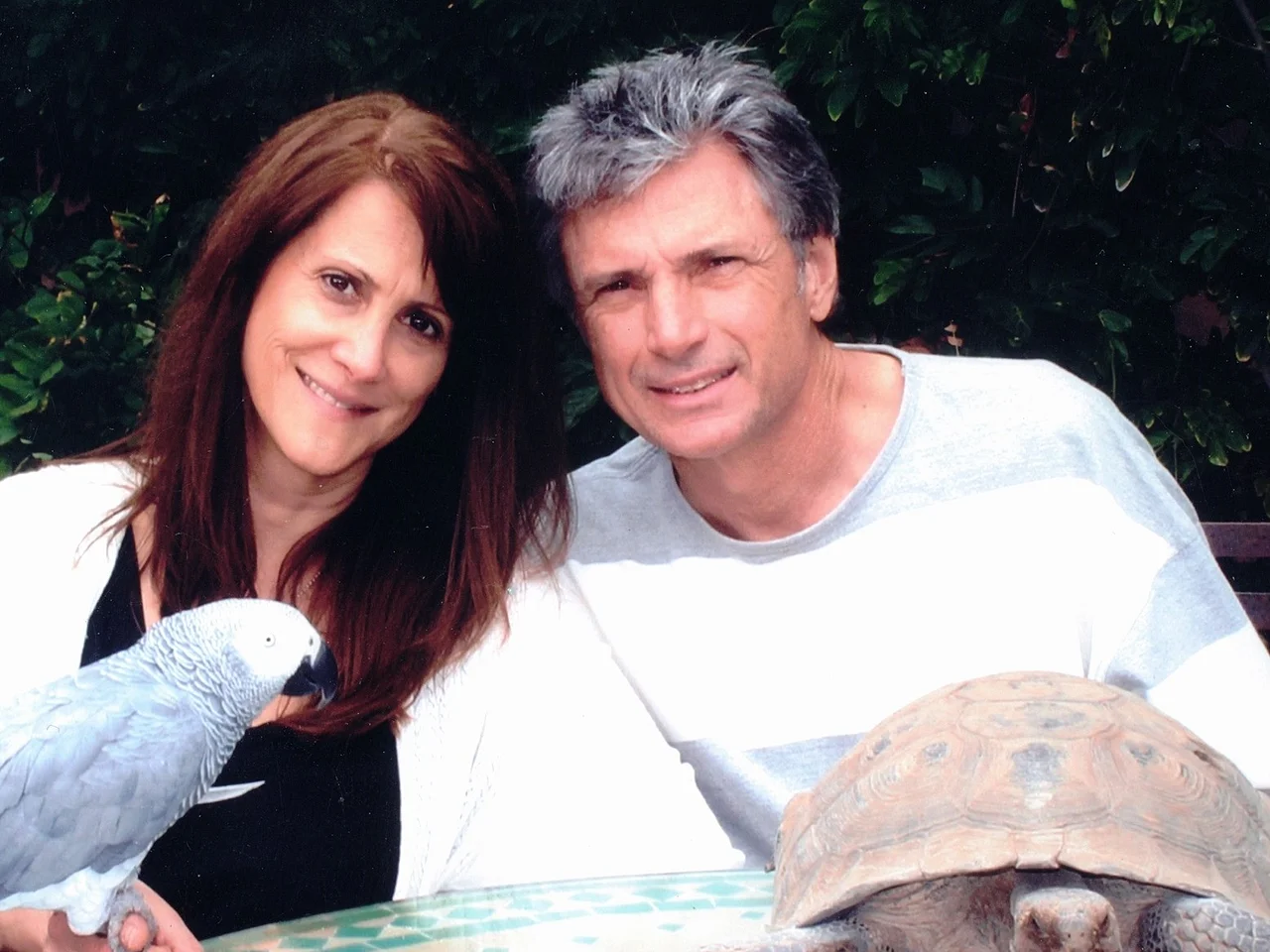 Rpbin Kaye und Thomas Deluca sitzen mit einem Papagei und einer Schildkröte im Garten und lächeln in die Kamera. - Foto: Facebook//robin.kaye.10