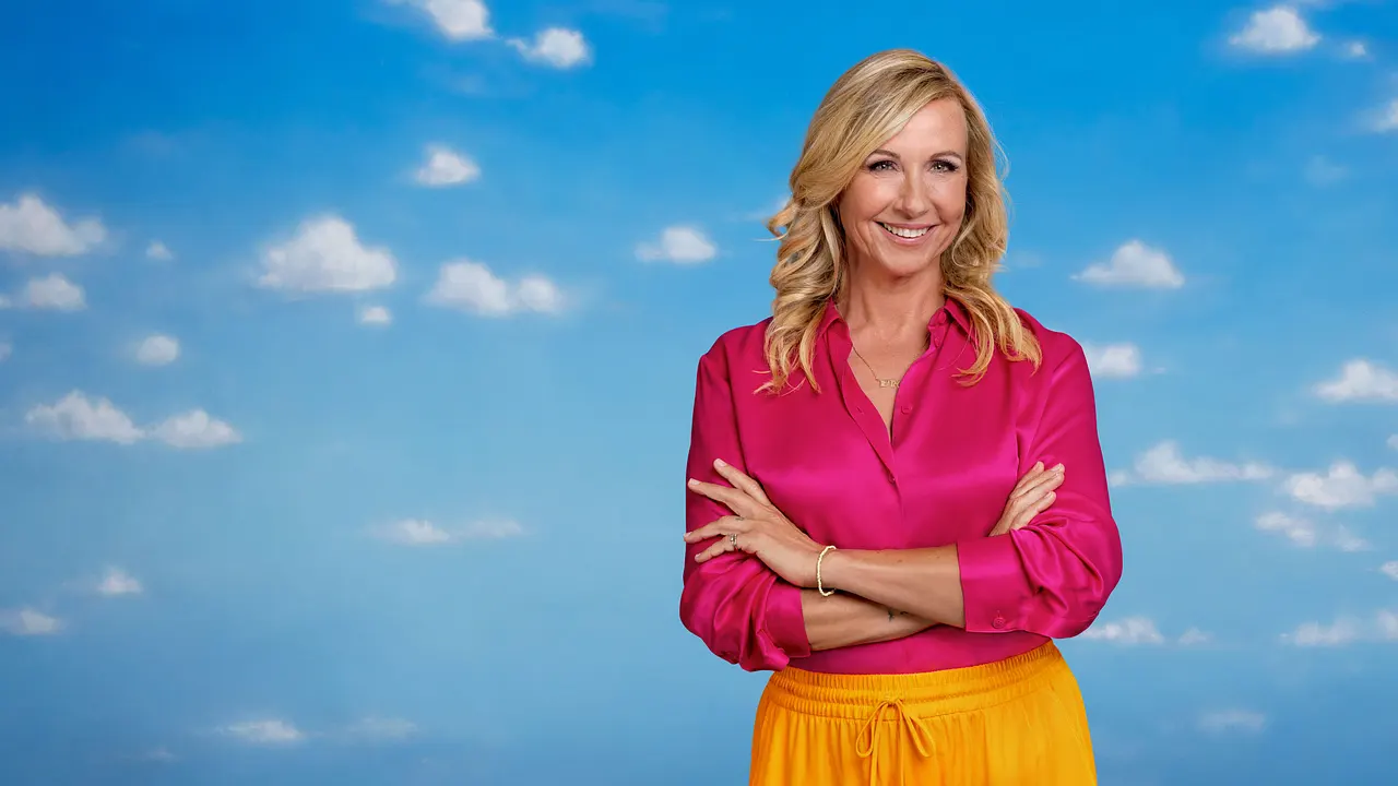 1299-25-20 Andrea Kiewel lächelt mit verschränkten Armen in die Kamera. Hinter ihr ist ein blauer Himmel mit kleinen, weißen Wolken zu sehen. - Foto: ZDF/Marcus Höhn