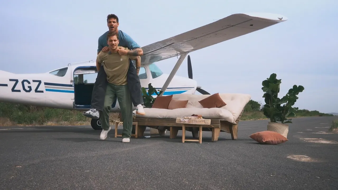 Felix nimmt Martin vor einem Flugzeug Huckepack.  - Foto: RTL