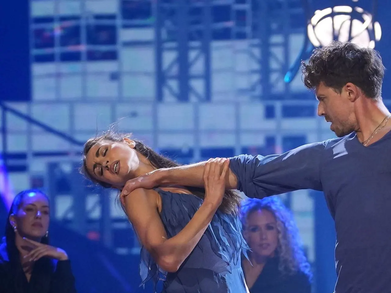 Ekaterina Leonova droht "Let's Dance"-Rauswurf Ekaterina Leonova und Valentin Lusin bei ihrer Sieges-Performance bei der Lets Dance-Profi-Challenge 2025 in blauen Outfits, im Hintergrund schwarz gekleidete Backup-Tänzer auf Stühlen. - Foto: RTL / Stefan Gregorowius