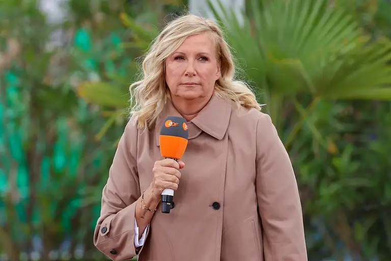 Andrea Kiewel moderiert den ZDF-Fernsehgarten mit einem Mikrofon in der Hand und sie schaut unzufrieden.