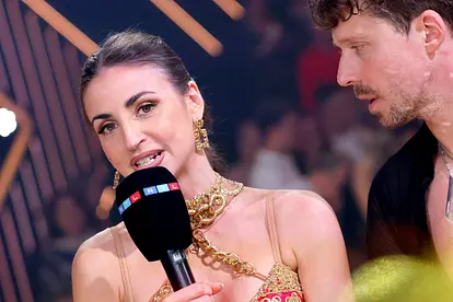 Ekaterina Leonova, hier im roten Kleid und dicker goldener Kette, spricht mit angestrengtem Blick in ein RTL-Mikrofon, Valentin Lusin schaut sie erschrocken an.