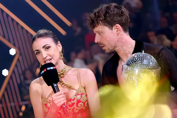 Ekaterina Leonova, hier im roten Kleid, spricht mit angestrengtem Blick in ein RTL-Mikrofon, Valentin Lusin schaut sie erschrocken an. 