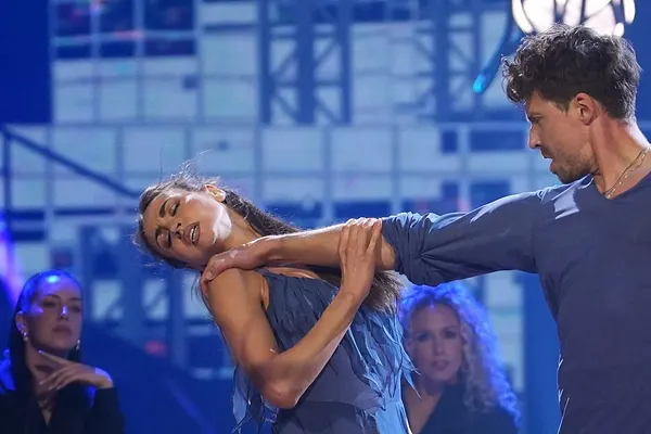 Ekaterina Leonova und Valentin Lusin bei ihrer Sieges-Performance bei der "Let's Dance"-Profi-Challenge 2025 in blauen Outfits, im Hintergrund schwarz gekleidete Backup-Tänzer auf Stühlen. 