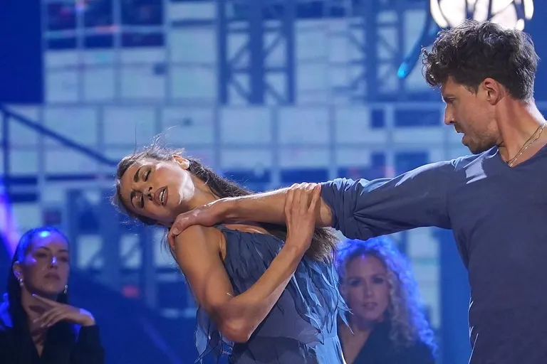 Ekaterina Leonova und Valentin Lusin bei ihrer Sieges-Performance bei der "Let's Dance"-Profi-Challenge 2025 in blauen Outfits, im Hintergrund schwarz gekleidete Backup-Tänzer auf Stühlen. 