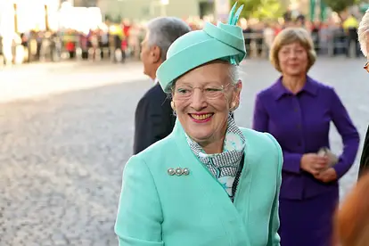 Königin Margrethe II. von Dänemark trägt ein mintgrünes Kostüm mit passendem Hund und lächelt an der Kamera vorbei.