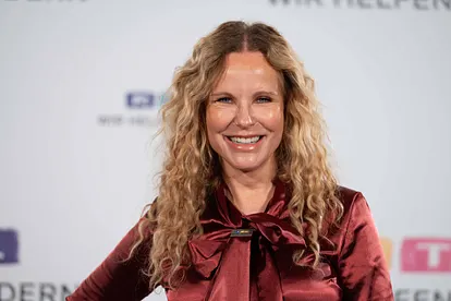 Katja Burkard auf dem roten Teppich beim RTL-Spendenmarathon "Wir helfen Kindern". Sie steht vor einer weißen Wand mit RTL-Logos und lächelt in die Kamera.