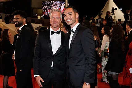 Ralf Schumacher und Lebensgefährte Étienne auf den Cannes Filmfestspielen. Beide lächeln in die Kamera und tragen einen schwarzen Anzug. 