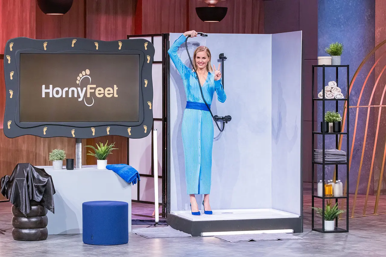 Janna Ensthaler steht im blauen Kleid und in farblich passenden Highheels unter einer Dusche im "Die Höhle der Löwen"-Studio.
