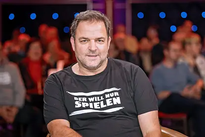 Martin Rütter im "Riverboat"-Studio. Er schaut in die Kamera, auf seinem schwarzen T-Shirt steht "Der will nur spielen".