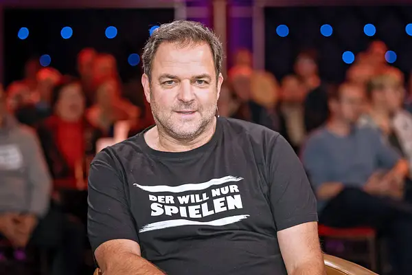 Martin Rütter im "Riverboat"-Studio. Er schaut in die Kamera, auf seinem schwarzen T-Shirt steht "Der will nur spielen".