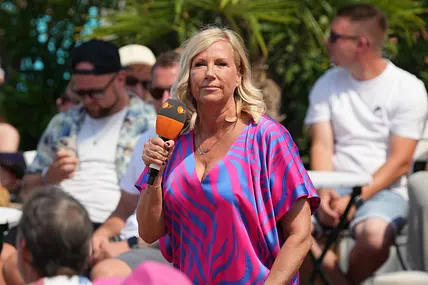Andrea Kiewel steht auf der Bühne vom "ZDF Fernsehgarten" und blickt ernst.