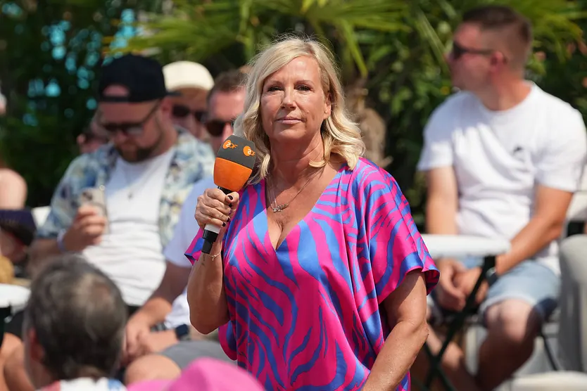 Andrea Kiewel steht auf der Bühne vom "ZDF Fernsehgarten" und blickt ernst.