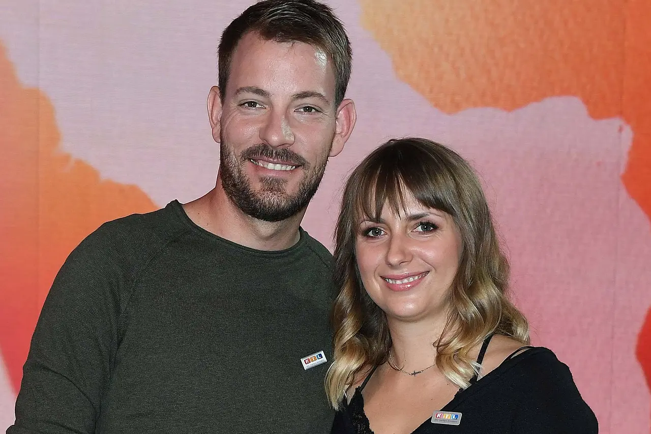 Anna Heiser und ihr Gerald Arm in Arm bei einem Event. Die beiden haben ein leichtes Lächeln auf dem Gesicht.