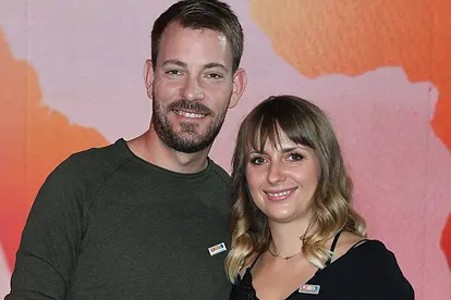 Anna Heiser und ihr Gerald Arm in Arm bei einem Event. Die beiden haben ein leichtes Lächeln auf dem Gesicht.