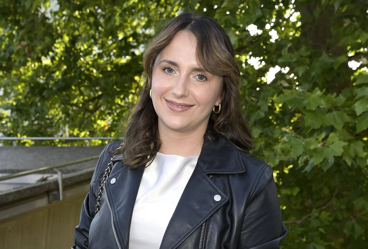 anna-heiser-erschöpft Anna Heiser posiert in Lederjacke vor einem Baum und lächelt - Foto: IMAGO / Future Image