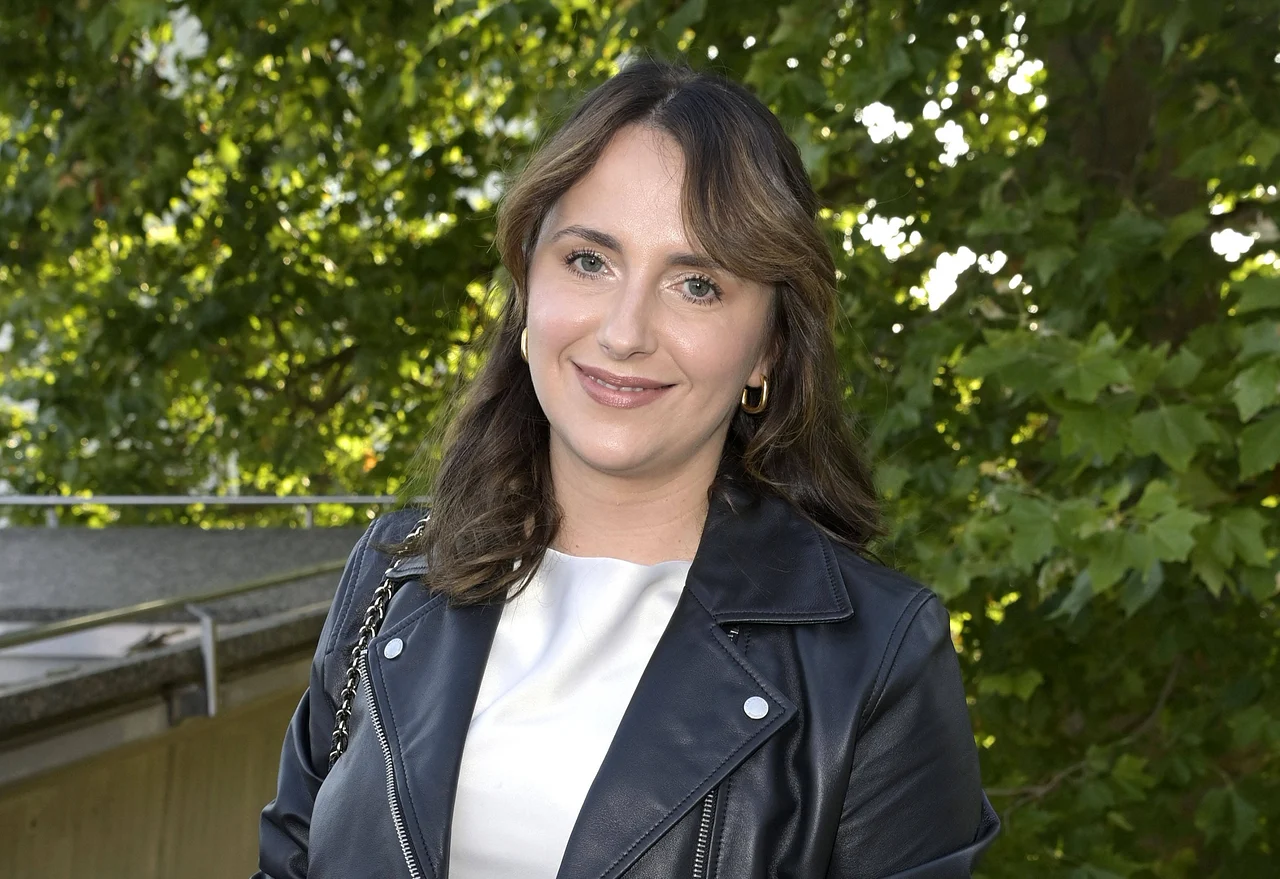 anna-heiser-traurige-wahrheit Anna Heiser trägt ein weißes Kleid und eine schwarze Lederjacke und lächelt in die Kamera. - Foto: IMAGO / Future Image