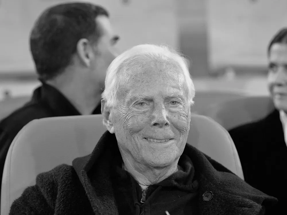 Giorgio Armani sitzt einem Stuhl und lächelt Giorgio Armani sitzt einem Stuhl und lächelt