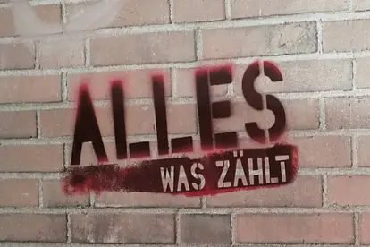 Das rote "Alles was zählt" Logo auf einer Backstein-Wand.
