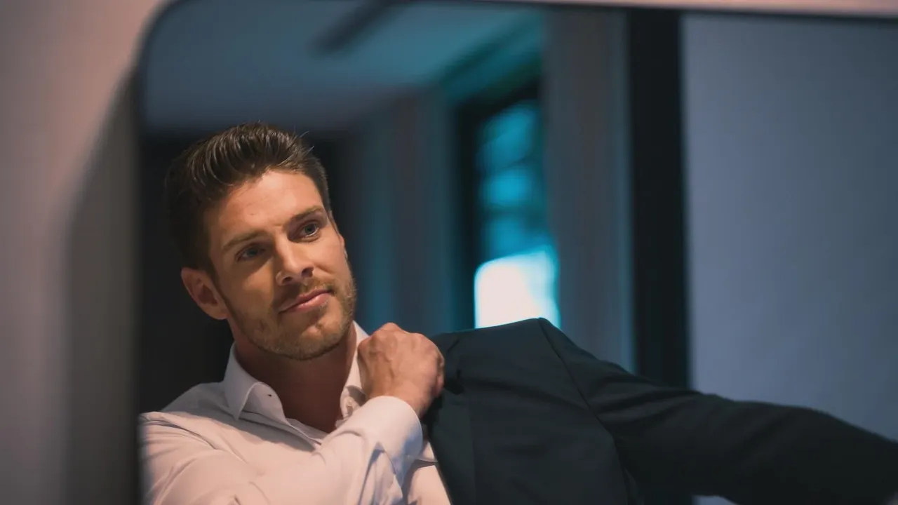 B8818 Bachelor Martin Braun schaut in einen Spiegel und zieht sich sein Jacket an - Foto: RTL