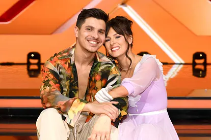 Patricija Ionel und ihr Mann Alexandru lächeln eng aneinandergelehnt auf den Stufen des "Let's Dance"-Studios in die Kamera.