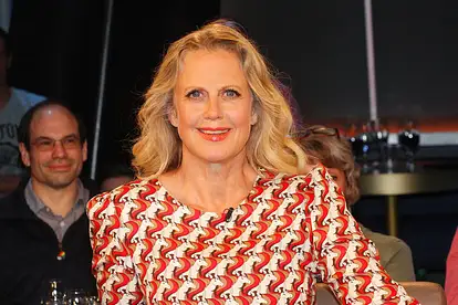 Barbara Schöneberger sitzt in einer Talkshow und lächelt in die Kamera.
