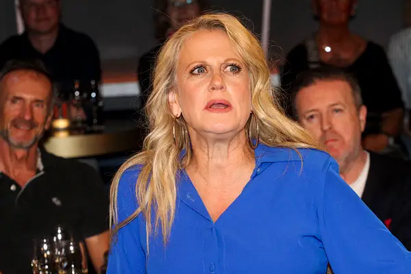 Barbara Schöneberger sitzt in einem blauen Hemd in einer Talkshow.