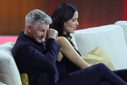 Ana Ivanovic und Bastian Schweinsteiger sitzen nebeneinander auf einer Couch. Sie blickt zu Boden, er reibt sich die Augen.