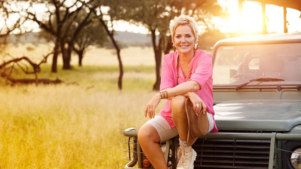 Inka Bause sitzt in der untergehenden Sonne auf einem Jeep in der Natur