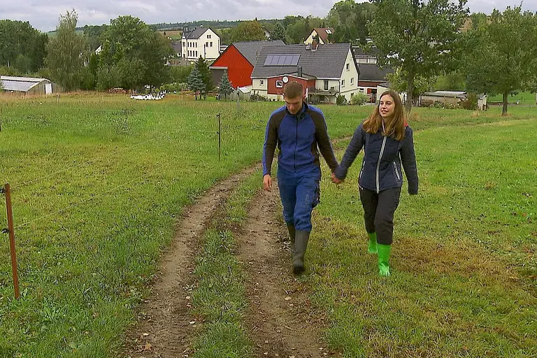 "Das Bauer sucht Frau"-Paar Anna und Paul läuft Hand in Hand über einen Wiesenweg. Sie wagen jetzt den nächsten Schritt.