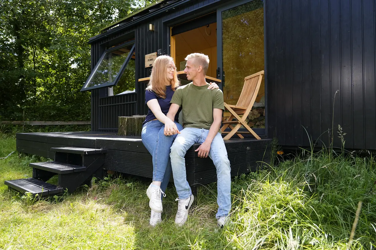 Pauline und Christopher von „Bauer sucht Frau“ sitzen vor einem Tiny House und sehen sich in die Augen.