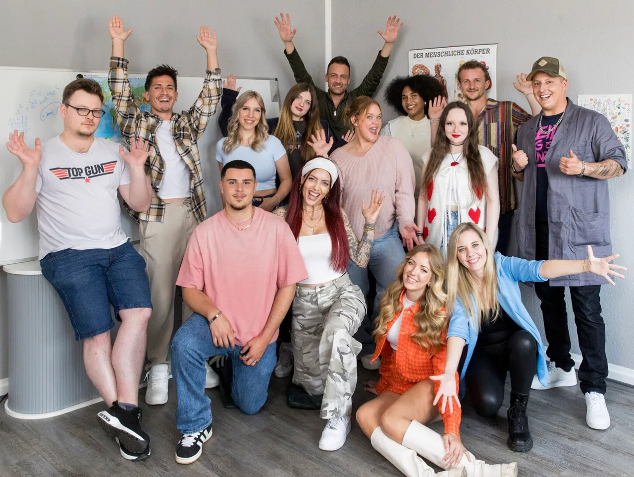 Bildschirmfoto 2025-06-11 um 12.28.16 Der Cast vom Serien-Comeback Krass Schule lächelt in die Kamera, dabei strecken neue und altbekannte Gesichter die Hände nach oben. - Foto: RTLZWEI