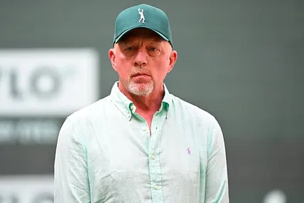 Boris Becker trägt ein hellgrünes Hemd und eine grüne Kappe und schaut ernst.