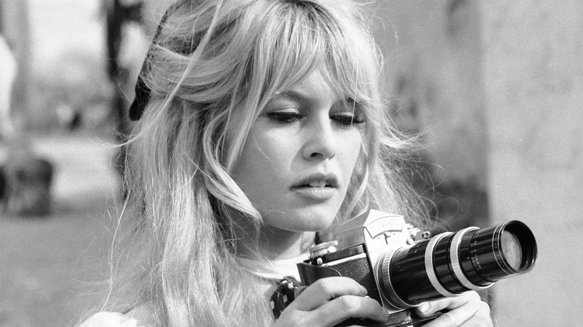 Brigitte Bardot hält eine Kamera in den Händen.