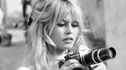 Brigitte Bardot hält eine Kamera in den Händen.