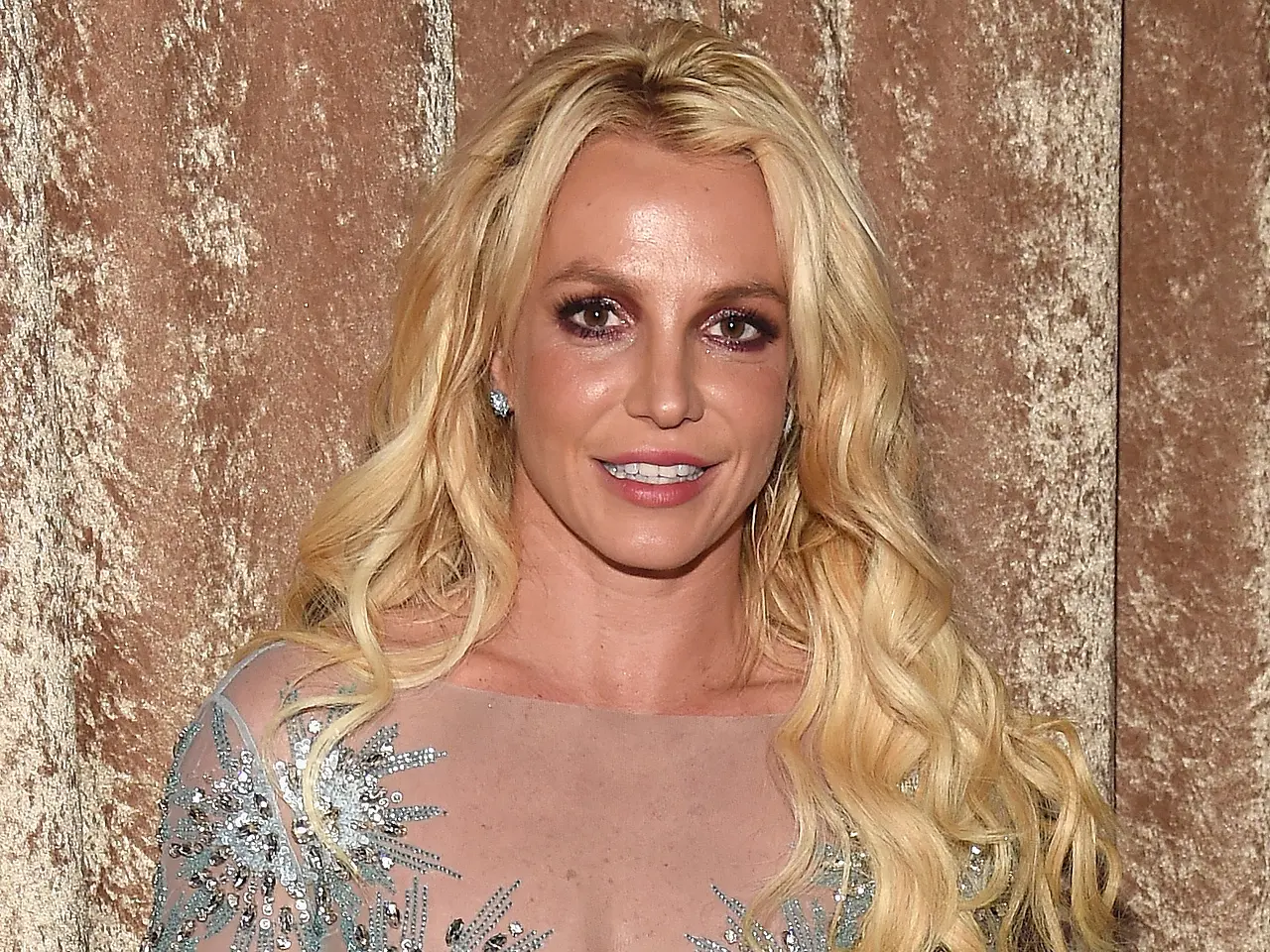 britney spears gettyimages 634805750 Britney Spears steht vor einem goldenen Samtvorhang und lächelt in die Kamera. - Foto: Kevin Mazur/WireImage/GettyImage
