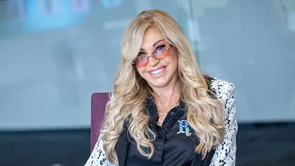 Carmen Geiss mit blonden Locken, rosaner Sonnenbrille und einer schwarzen Bluse mit Ärmeln aus weißer Spitze
