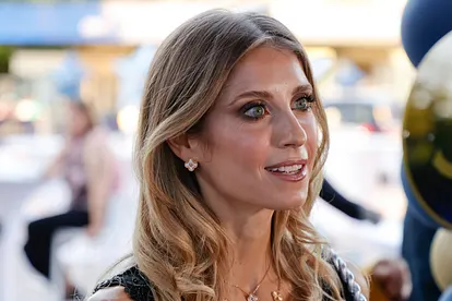 Cathy Hummels wird lächelnd von der Seite fotografiert. Sie trägt offene Haare und hat stark geschminkte Augen.