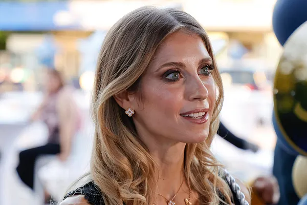 Cathy Hummels wird lächelnd von der Seite fotografiert. Sie trägt offene Haare und hat stark geschminkte Augen.