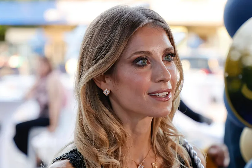 Cathy Hummels wird lächelnd von der Seite fotografiert. Sie trägt offene Haare und hat stark geschminkte Augen.