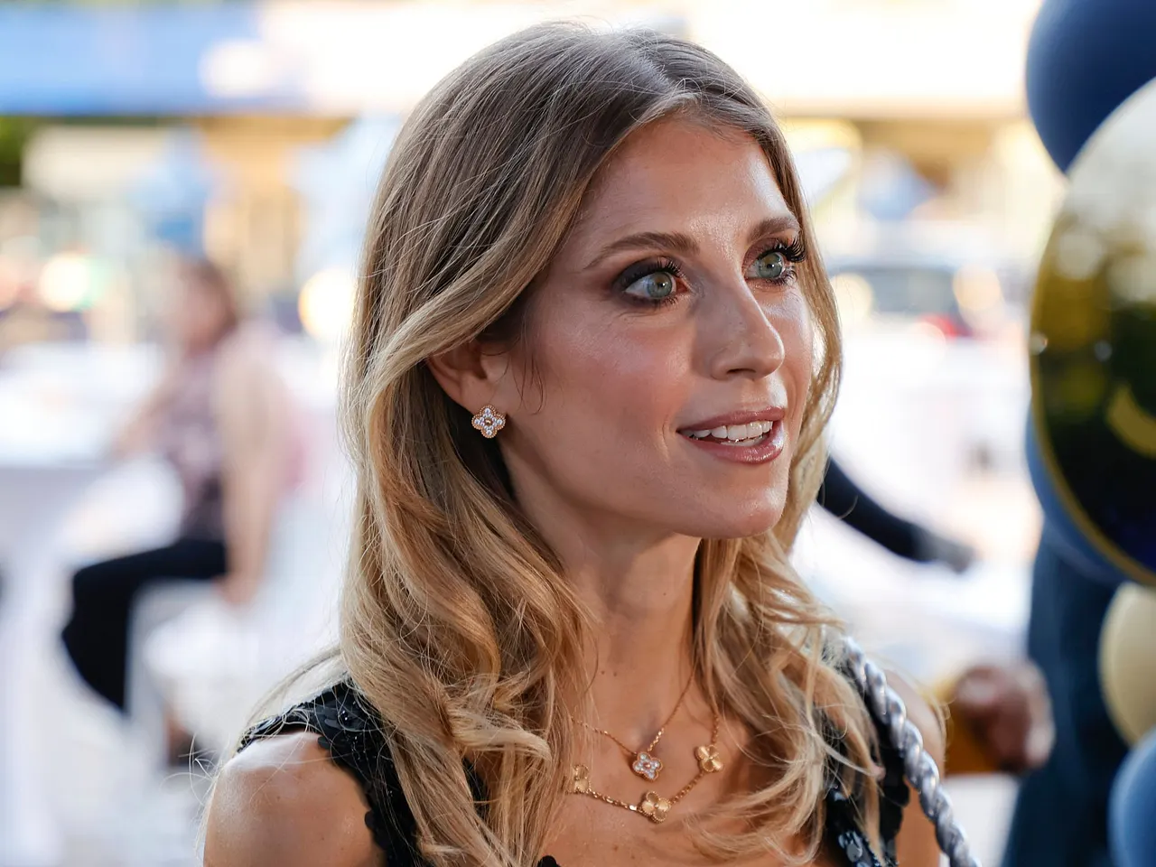 Cathy Hummels wird lächelnd von der Seite fotografiert. Sie trägt offene Haare und hat stark geschminkte Augen. - Foto: IMAGO / Mandoga Media