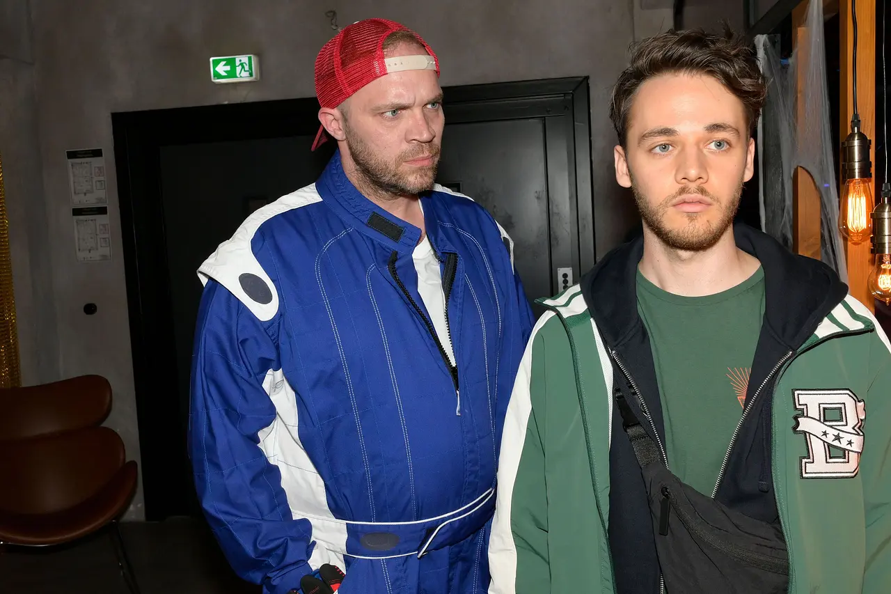 Robin schaut resigniert nach vorne, während Erik ihn wütend anstarrt.