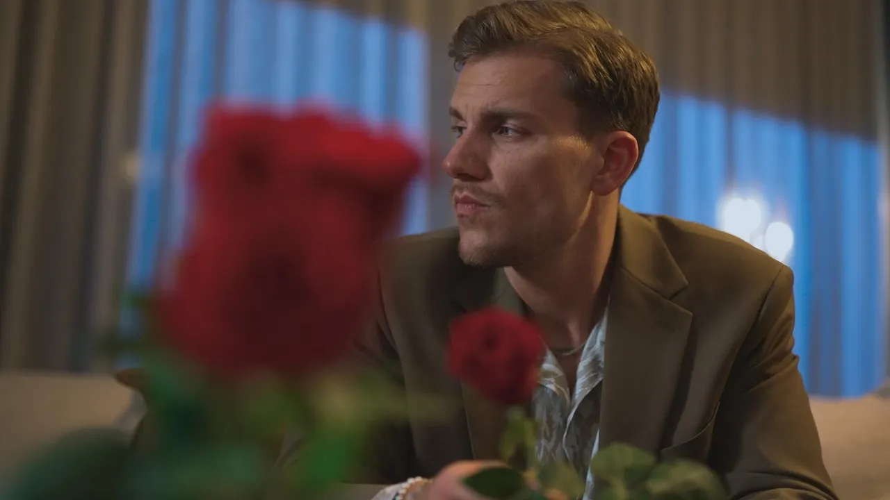 Bachelor Felix Stein schaut nachdenklich in eine Richtung, vor ihm sind verschwommen zwei Rosen - Foto: RTL