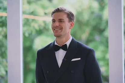 Bachelor Felix Stein strahlt im Smoking seine Kandidatinnen an
