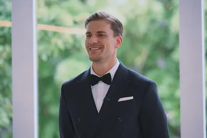 Bachelor Felix Stein strahlt im Smoking seine Kandidatinnen an