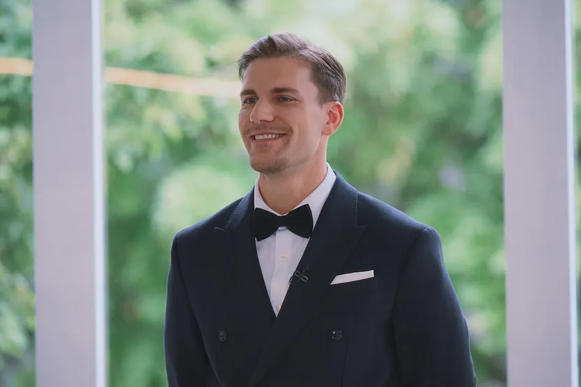 Bachelor Felix Stein strahlt im Smoking seine Kandidatinnen an