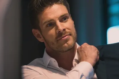 Bachelor Martin Braun schaut in einen Spiegel und zieht sich sein Jacket an