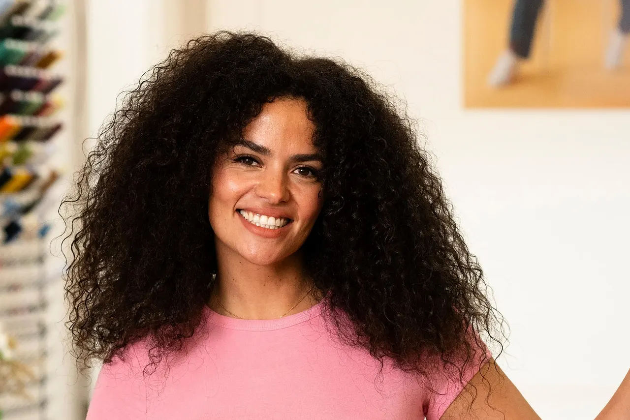 Vivi von "Die Bachelors" posiert mit ihrer linken Hand an der Wand lehnend lächelnd in die Kamera