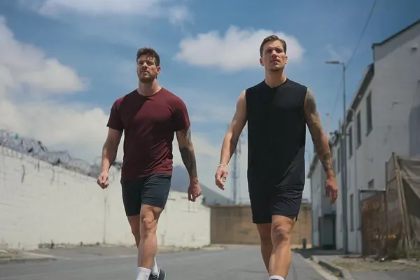 Martin Braun und Felix Stein, die Bachelors, laufen in Sportoutfits eine verlassene Straße entlang.