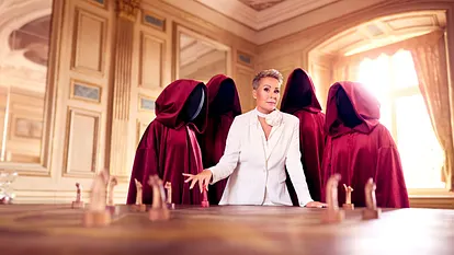 Sonja Zietlow ist umgeben von gesichtslosen Personen in roten Roben. Vor ihr steht ein Schachbrett.